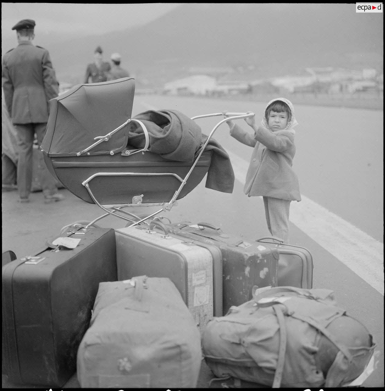 Enfant avec un landeau attendant au port d'Oran le départ pour la France.